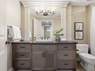 This bathroom features a spacious vanity with ample storage and a granite countertop, complemented by a modern vessel sink and elegant fixtures.
