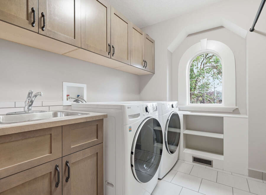 This spacious laundry room features a convenient utility sink and ample storage with custom cabinetry.