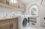 This spacious laundry room features a convenient utility sink and ample storage with custom cabinetry.
