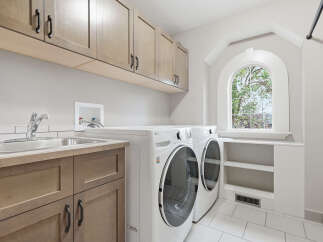 This spacious laundry room features a convenient utility sink and ample storage with custom cabinetry.