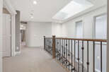 This spacious hallway features a beautiful wooden banister leading down a carpeted staircase.