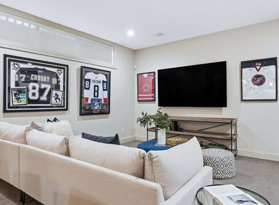 This modern living room features a large sectional sofa perfect for family gatherings, complemented by a sleek entertainment center housing a big screen TV.