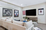 This modern living room features a large sectional sofa perfect for family gatherings, complemented by a sleek entertainment center housing a big screen TV.