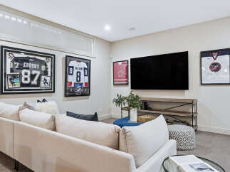 This modern living room features a large sectional sofa perfect for family gatherings, complemented by a sleek entertainment center housing a big screen TV.