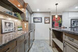 This basement bar area features a granite countertop with a stainless steel sink and faucet, complemented by custom wood cabinetry.