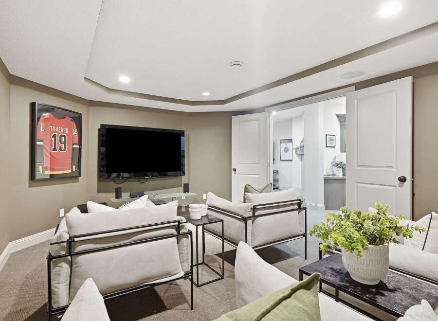 This inviting living room features a large flat-screen TV mounted above a sleek glass shelf, perfect for entertainment.