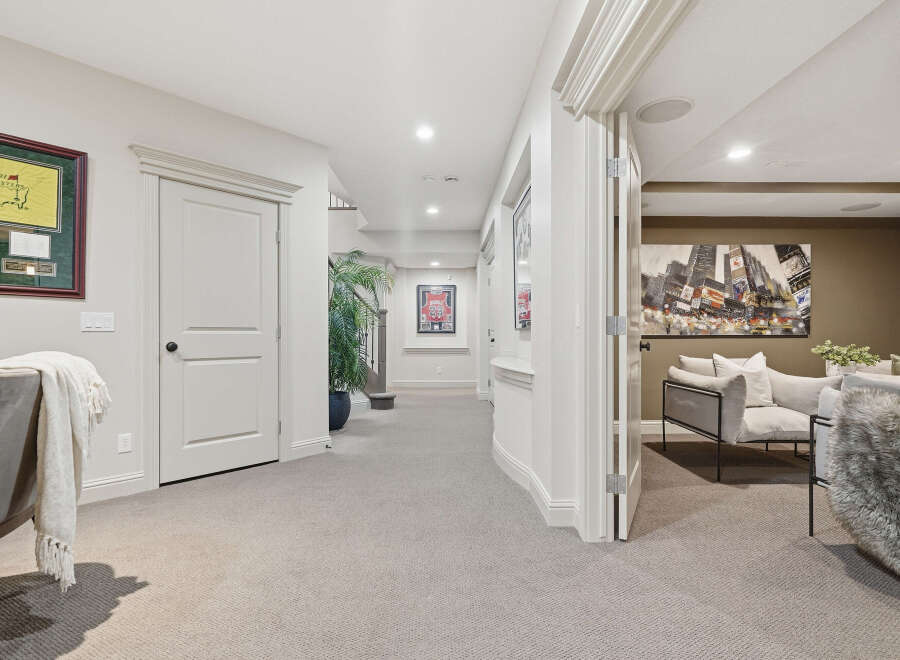 Step into a beautifully finished basement featuring a spacious hallway with elegant trim and a framed golf memorabilia piece.