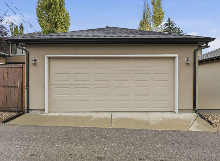 This property features a well-maintained garage with a classic beige sectional door, perfect for protecting your vehicles.