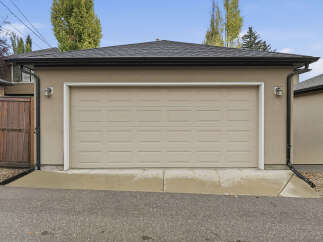 This property features a well-maintained garage with a classic beige sectional door, perfect for protecting your vehicles.
