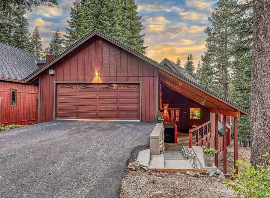 Nestled amidst towering pine trees, this charming red wood-sided home offers a serene mountain retreat.