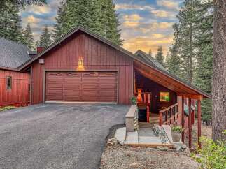 Nestled amidst towering pine trees, this charming red wood-sided home offers a serene mountain retreat.
