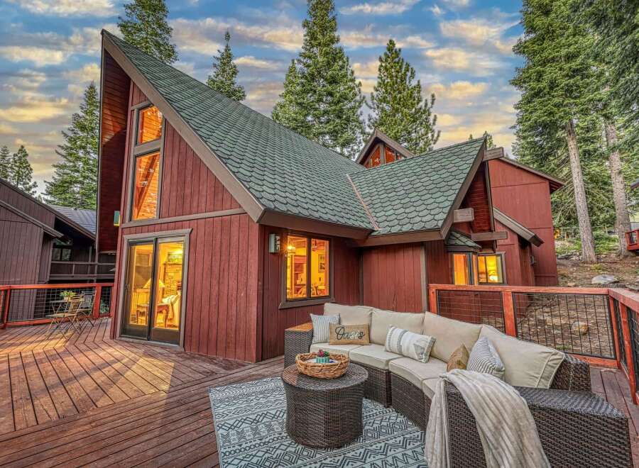 Experience mountain living in this stunning A-frame home, featuring a spacious wooden deck perfect for outdoor entertaining.