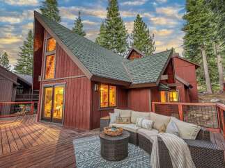 Experience mountain living in this stunning A-frame home, featuring a spacious wooden deck perfect for outdoor entertaining.