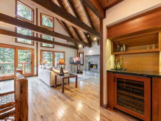 Experience rustic luxury in this stunning living space, featuring a soaring vaulted ceiling with exposed wooden beams and a charming stone fireplace.