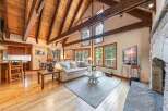 Experience rustic charm in this spacious living area featuring a vaulted wood-beamed ceiling and a grand stone fireplace.