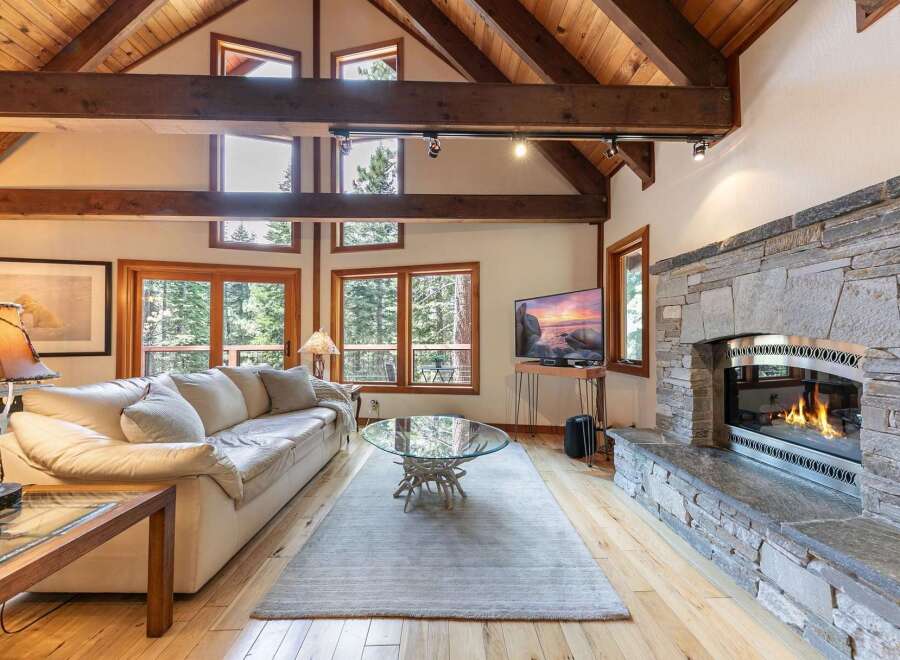 Experience rustic charm and modern comfort in this stunning living room, featuring a grand stone fireplace and soaring vaulted ceilings with exposed wooden beams.