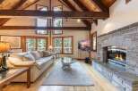 Experience rustic charm and modern comfort in this stunning living room, featuring a grand stone fireplace and soaring vaulted ceilings with exposed wooden beams.