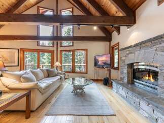 Experience rustic charm and modern comfort in this stunning living room, featuring a grand stone fireplace and soaring vaulted ceilings with exposed wooden beams.