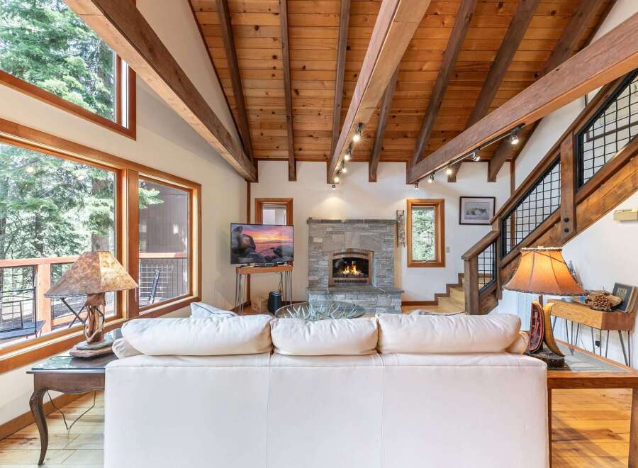 Experience rustic charm in this inviting living room, featuring a magnificent stone fireplace and a soaring wood-beamed ceiling.