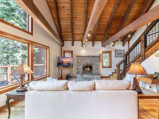 Experience rustic charm in this inviting living room, featuring a magnificent stone fireplace and a soaring wood-beamed ceiling.