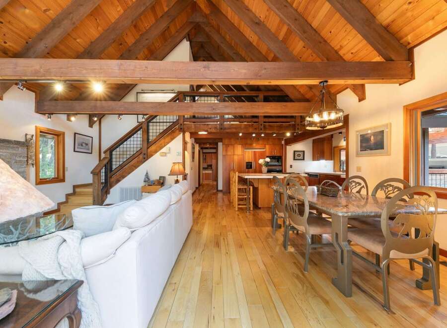 Experience rustic charm in this spacious open-concept living area, featuring a soaring vaulted wood-beam ceiling and a cozy stone fireplace.