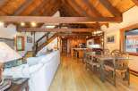 Experience rustic charm in this spacious open-concept living area, featuring a soaring vaulted wood-beam ceiling and a cozy stone fireplace.