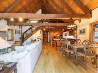 Experience rustic charm in this spacious open-concept living area, featuring a soaring vaulted wood-beam ceiling and a cozy stone fireplace.
