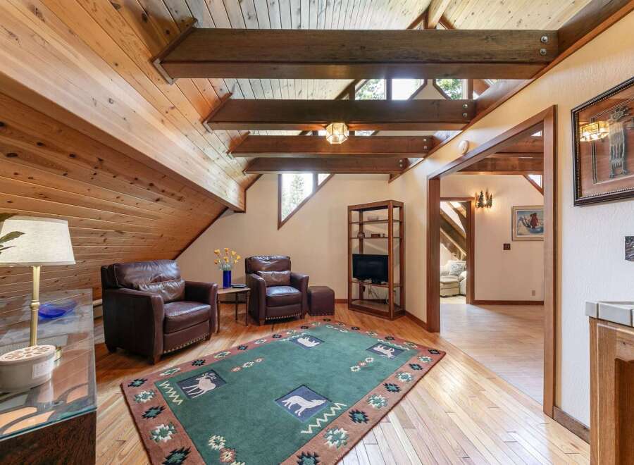 Experience rustic charm in this inviting living space, featuring a vaulted wood-paneled ceiling with exposed beams and ample natural light.