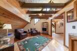 Experience rustic charm in this inviting living space, featuring a vaulted wood-paneled ceiling with exposed beams and ample natural light.