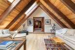 Experience rustic charm in this attic living space, featuring exposed wooden beams and a vaulted ceiling with skylights that flood the room with natural light.