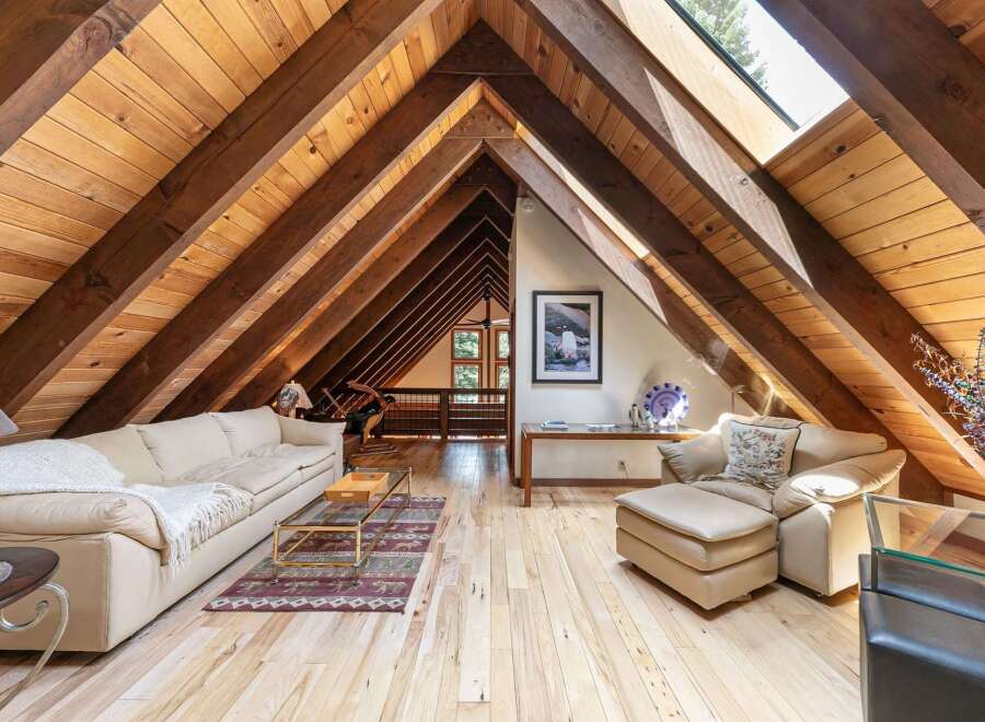 Experience rustic charm in this stunning attic living space, featuring exposed wooden beams and a vaulted ceiling that creates an airy, open atmosphere.