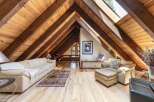 Experience rustic charm in this stunning attic living space, featuring exposed wooden beams and a vaulted ceiling that creates an airy, open atmosphere.