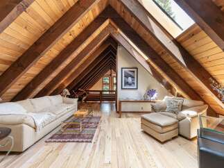 Experience rustic charm in this stunning attic living space, featuring exposed wooden beams and a vaulted ceiling that creates an airy, open atmosphere.