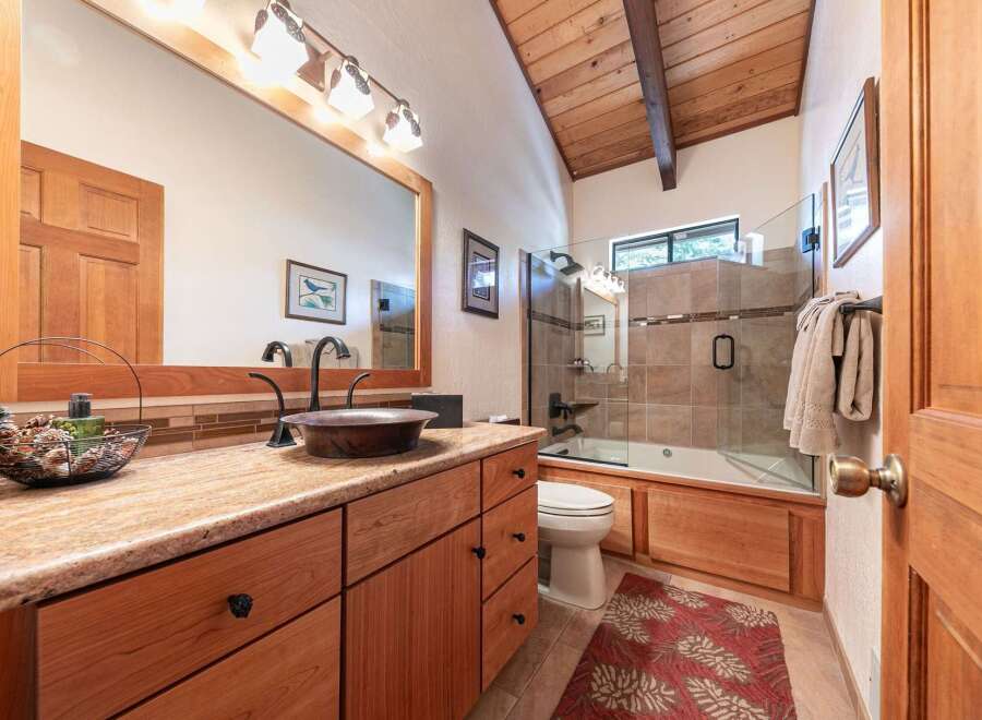 This charming bathroom boasts a rustic aesthetic with its exposed wooden beams and natural wood cabinetry.