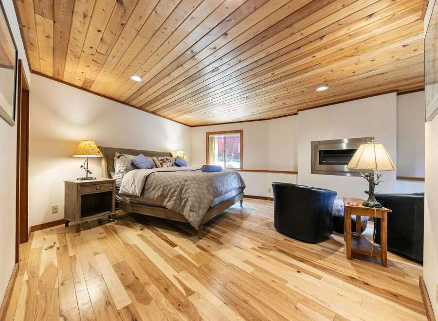 Experience rustic charm in this inviting bedroom, featuring a beautifully paneled wood ceiling and warm hardwood floors.