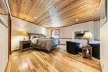 Experience rustic charm in this inviting bedroom, featuring a beautifully paneled wood ceiling and warm hardwood floors.