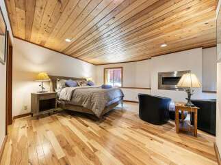 Experience rustic charm in this inviting bedroom, featuring a beautifully paneled wood ceiling and warm hardwood floors.