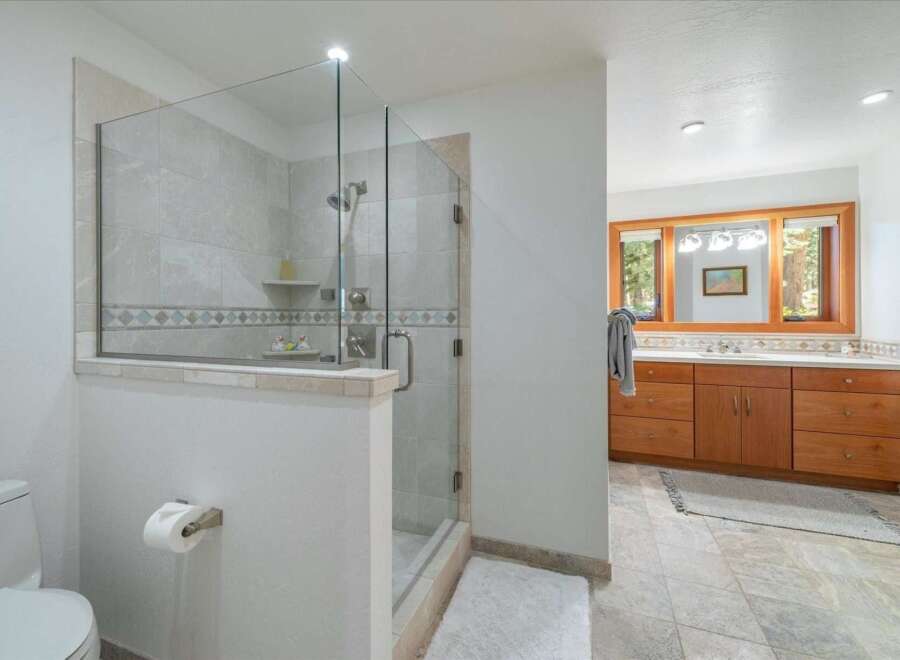 Experience luxury in this spacious bathroom featuring a modern glass-enclosed shower with elegant tilework.