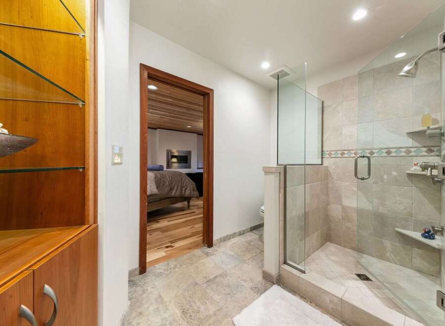 Experience luxury in this master bathroom featuring a spacious glass-enclosed shower with elegant tile work and a modern showerhead.
