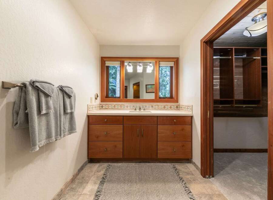 This bathroom boasts a spacious vanity with ample storage, complemented by a large mirror offering views of the outdoors.