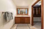 This bathroom boasts a spacious vanity with ample storage, complemented by a large mirror offering views of the outdoors.