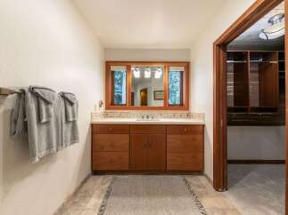 This bathroom boasts a spacious vanity with ample storage, complemented by a large mirror offering views of the outdoors.