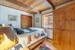 Experience rustic charm in this cozy bedroom, featuring a wooden beamed ceiling and a nature-themed comforter.