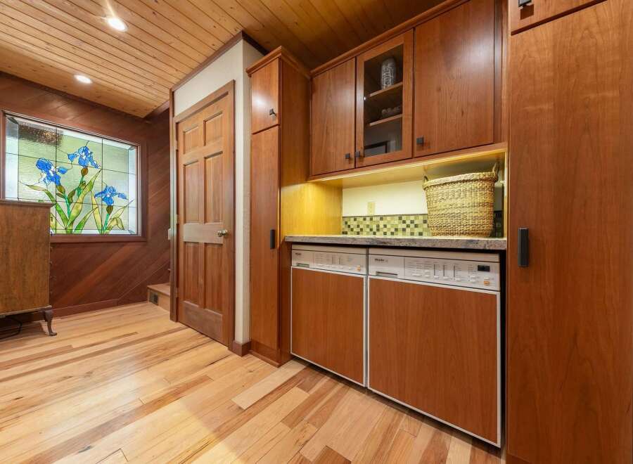 Step into a charming entryway featuring warm wood paneling and a beautiful stained-glass window depicting blue irises.