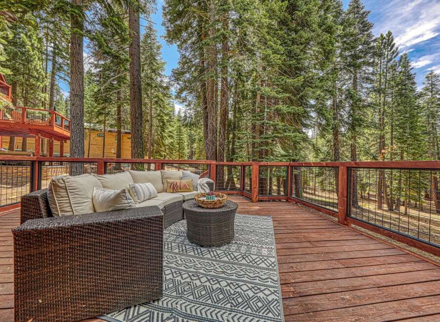 Enjoy the serene mountain lifestyle on this expansive deck, perfect for outdoor entertaining amidst towering pine trees.
