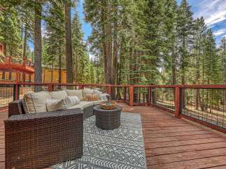Enjoy the serene mountain lifestyle on this expansive deck, perfect for outdoor entertaining amidst towering pine trees.