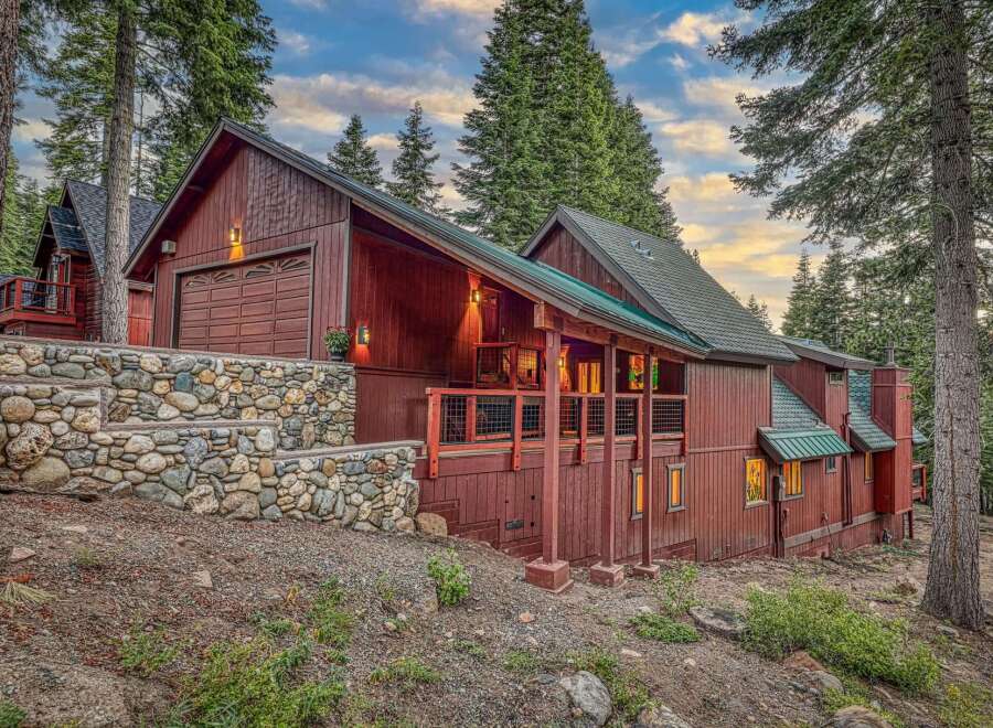 Nestled amidst towering pine trees, this stunning mountain home boasts a rustic charm with its rich wooden exterior and natural stone accents.