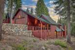 Nestled amidst towering pine trees, this stunning mountain home boasts a rustic charm with its rich wooden exterior and natural stone accents.