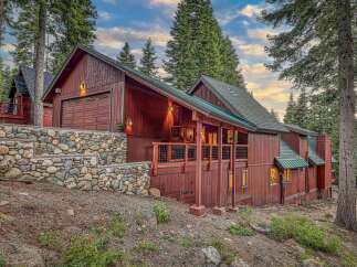 Nestled amidst towering pine trees, this stunning mountain home boasts a rustic charm with its rich wooden exterior and natural stone accents.