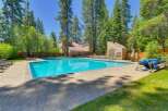 Enjoy a refreshing dip in the sparkling blue swimming pool, surrounded by lush green trees and a paved patio area.